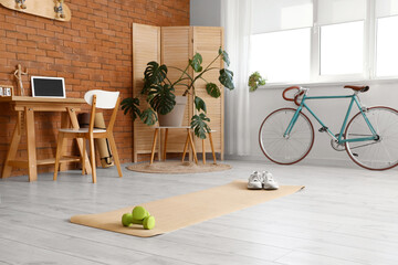 Interior of office with workplace, sports equipment and bicycle