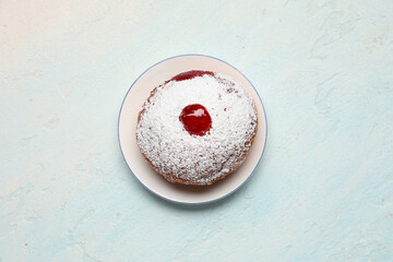 Tasty donut with jam for Hanukkah celebration on light blue background