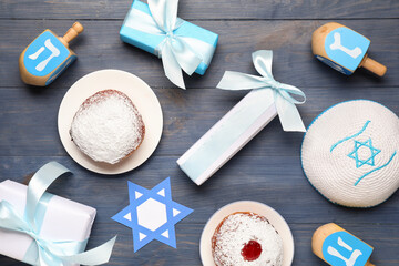 Hanukkah composition with dreidels, donuts and gift boxes on blue wooden background