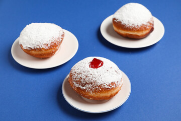 Tasty donuts with jam for Hanukkah celebration on blue background, closeup