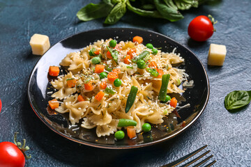 Plate with tasty pasta primavera on black background