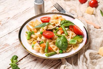 Plate with tasty pasta primavera on white wooden background