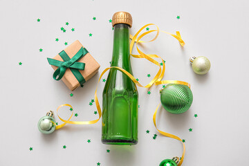 Bottle of champagne with Christmas balls and gift box on grey background