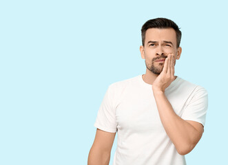 Handsome man with toothache on blue background