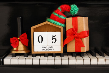 Calendar with text 5 DAYS UNTIL HOLIDAYS, Christmas gift and decor on piano keys
