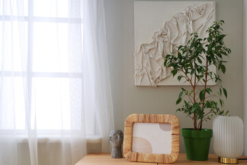 Green plant with frame, lamp and decor on table in room