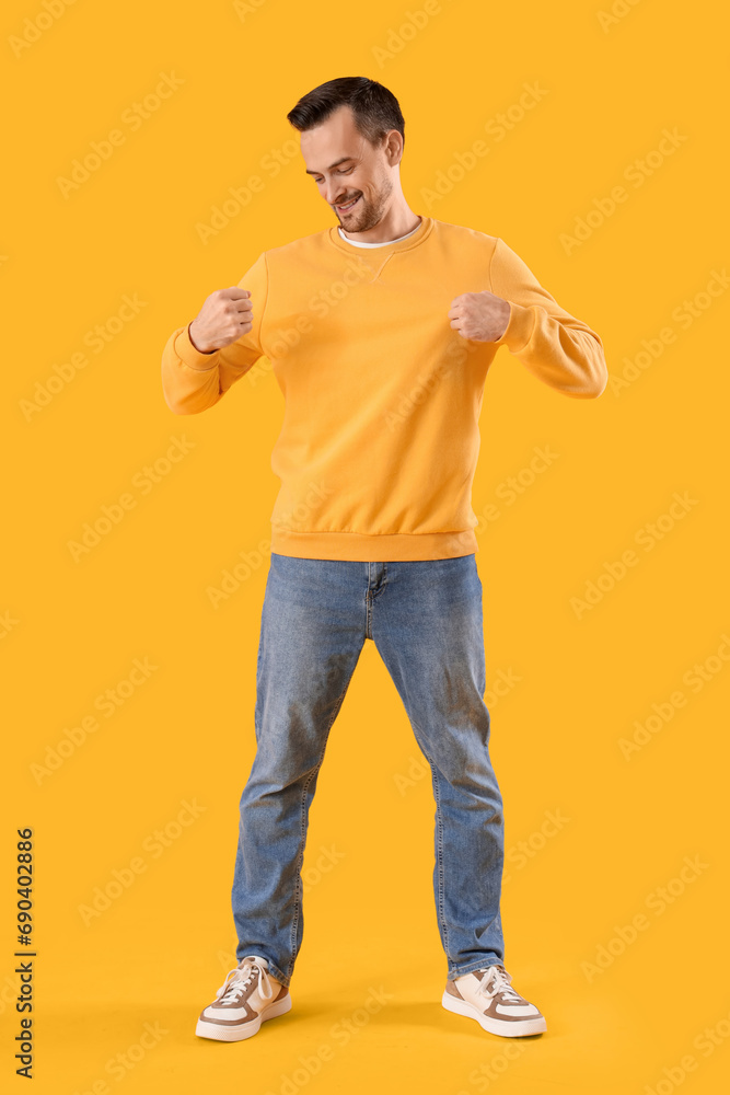 Wall mural young man in sweatshirt on yellow background