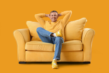 Obraz premium Mature man resting on sofa against yellow background