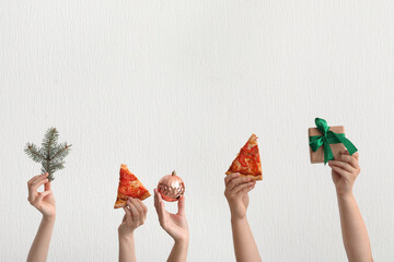 Female hands with pizza slices and Christmas decor on white background