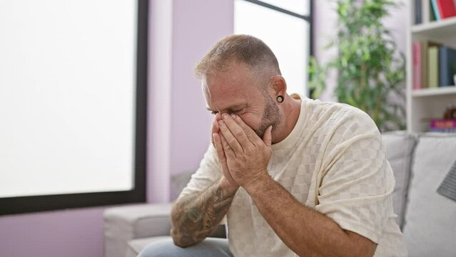 Young man sitting on sofa crying at home