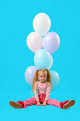 Cute little girl with beautiful balloons sitting on blue background