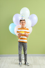 Cute little boy with balloons and Birthday cake near green wall