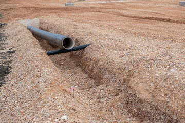Laying sewer drainage pipe on constriction site. Digged New sanitary sewer, storm drain systems - obrazy, fototapety, plakaty