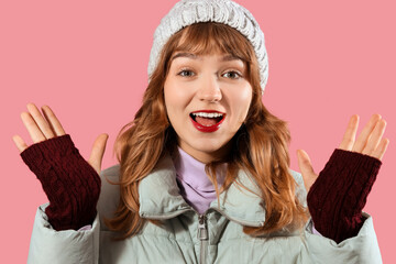 Smiling young woman in winter clothes on pink background, closeup