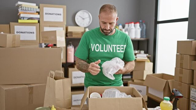 Attractive young man passionately volunteering at charity center, packing cardboard boxes for donations in a unified community effort