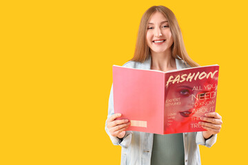 Young happy pregnant woman reading magazine on yellow background