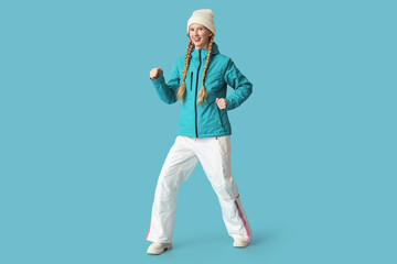 Beautiful young happy woman in warm winter clothes on blue background