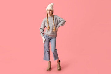 Beautiful young happy woman in warm winter clothes on pink background