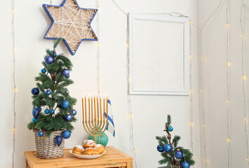 Wooden table with fir tree, menorah and sufganiyots in living room