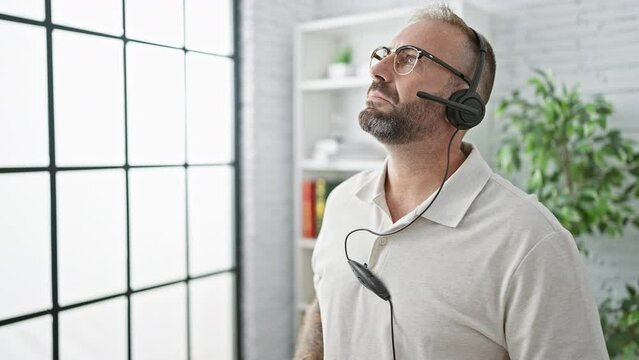 Handsome young business man, a successful worker at an indoor office, concentrating on a free hands call, seriously speaking into microphone