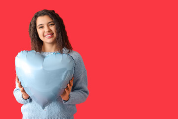 Fototapeta na wymiar Happy young woman with heart shaped air balloon on red background