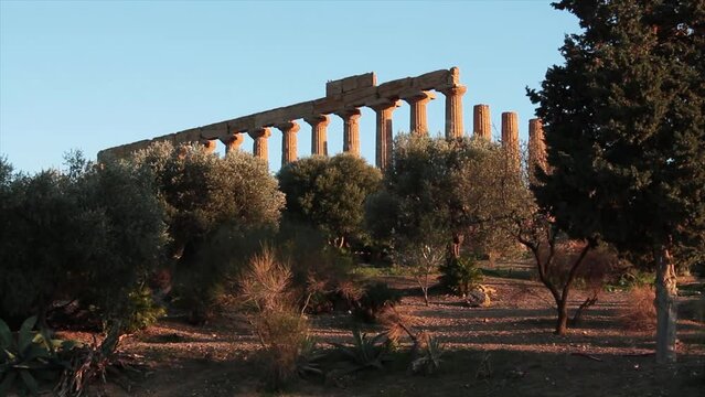 agrigento sicily italy ancient temple of juno pillars on mountain top peak hill wide shot with trees in foreground