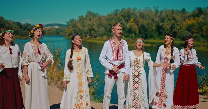 Ritual chants of ancient Slavic on river shore in summer feast, people in national gowns, 4K, Prores