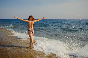 A tranquil scene as a woman with arms wide open welcomes the embrace of the sea