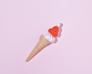 Ice cream with a woolen cap in the style of Santa Claus, minimal Christmas holiday concept.