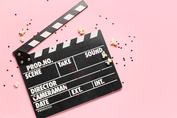 Movie clapper with popcorn and confetti on pink background. Valentine's Day celebration