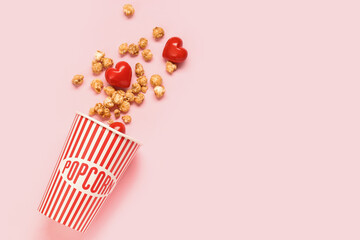 Bucket of popcorn and hearts on pink background. Valentine's Day celebration