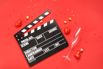 Movie clapper with popcorn, champagne glass and hearts on red background. Valentine's Day...