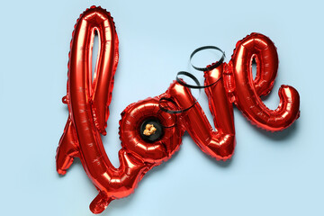 Air balloons in shape of word LOVE with film reel and popcorn on blue background. Valentine's Day celebration