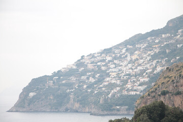 amalfi coast mountain tip next to ocean water town village homes houses, wide medium shot