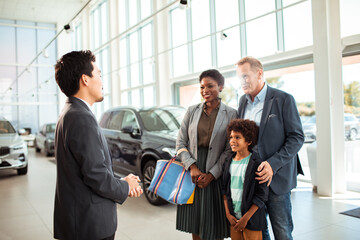 Family at car dealership talking to salesman