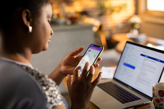 Woman using smartphone for online banking at home