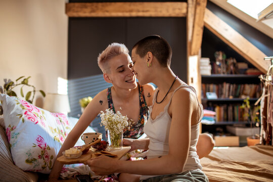 Young female couple having breakfast in bed in the bedroom
