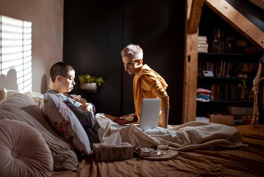 Young woman helping her sick girlfriend in the bedroom