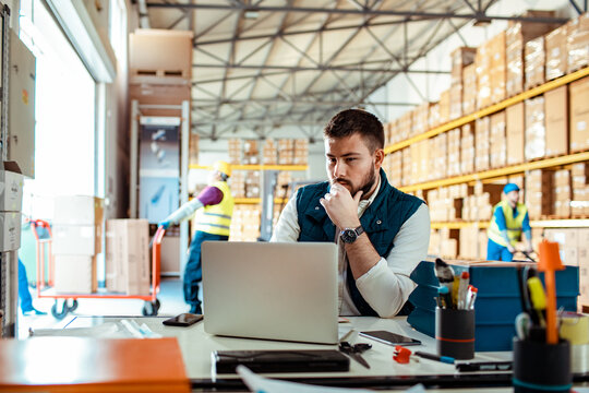 Professional male manager using laptop in warehouse