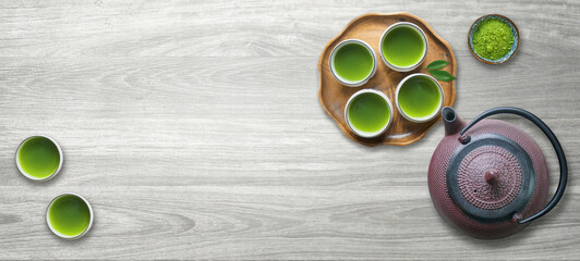 Cups of green tea with cast iron tea pot or kettle and fresh matcha powder                        