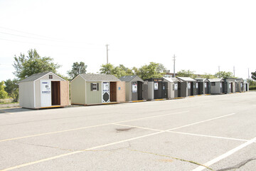 line row of sheds on sale for sale in parking lot middle of frame