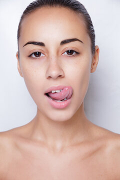 Beautiful woman sticking out her tongue and showing young piercing