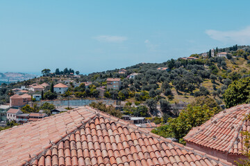 Tiled roofs with the groves of olive trees background with blue sky on the sunny day for publication, poster, calendar, post, screensaver, wallpaper, banner, cover. High quality photo