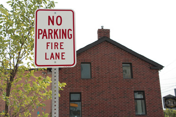 no parking fire lane vertical rectangle vintage style sign on post with red brick house home...