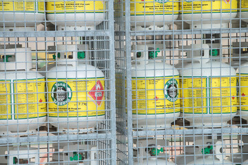 propane tanks on shelves in cages atop one another outside during summer, close up
