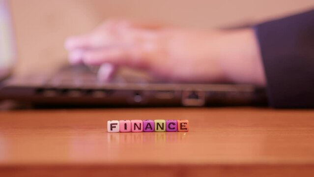 Finances concept. Hands of the person working on laptop with beads forming word finance. High quality 4k footage
