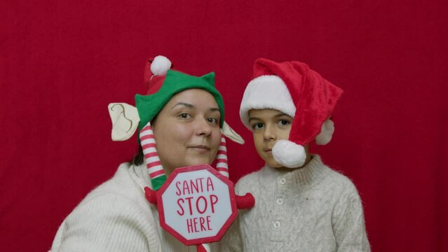 Mom and son holding santa stop here sign, Family bonding during the cristmas holidays. High quality 4k footage