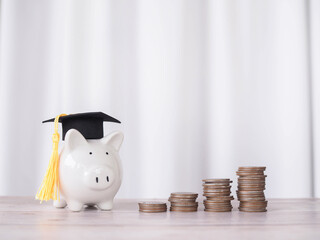 Piggy bank with graduation hat and stack of coins. The concept of saving money for education, student loan, scholarship, tuition fees in future - obrazy, fototapety, plakaty