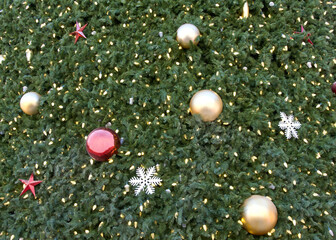 Close up of giant Christmas tree with ornaments, balls and snow flakes and lights bright.