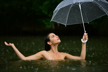 Sexy naked Woman with umbrella in water. Summer rain. Rainy weather. Rain rain go away. Sexy woman sensually relaxing in water. Recreation wellness and wellbeing. Sensual rain. Sexy wet female body.